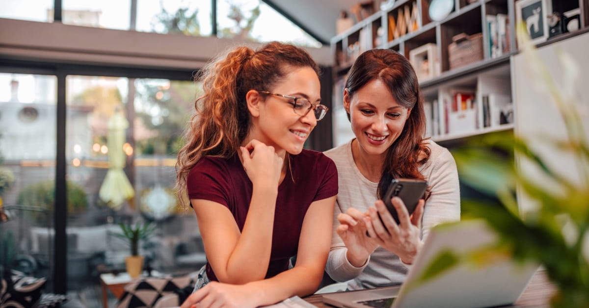 Duas mulheres olhando para um smartphone e pesquisando frases para bio do Instagram