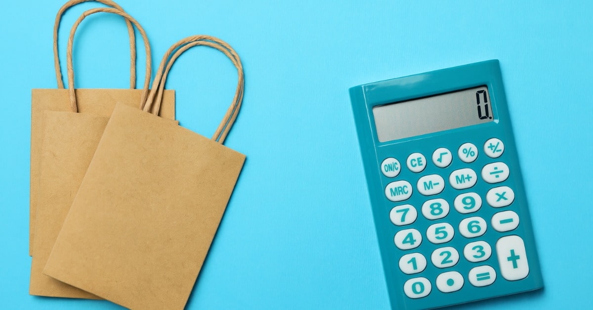 Calculadora azul ao lado de sacolas de loja ilustrando o conceito de como calcular preço de venda