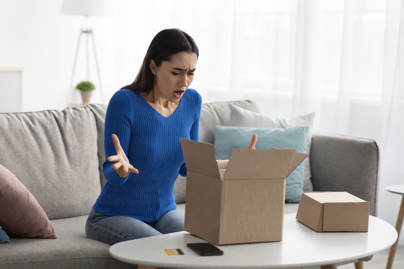 Mulher abre caixa de pedido danificado representando extravio, avaria e roubo de pacote