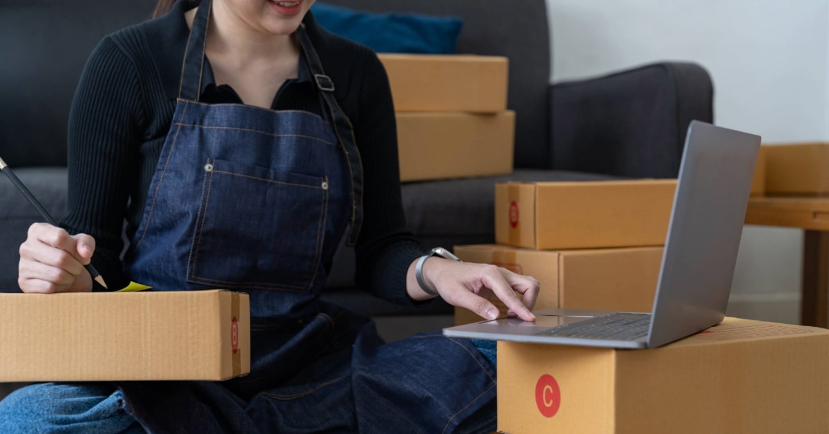 Empreendedora separando caixas de entrega enquanto faz otimização logística dos seus pedidos