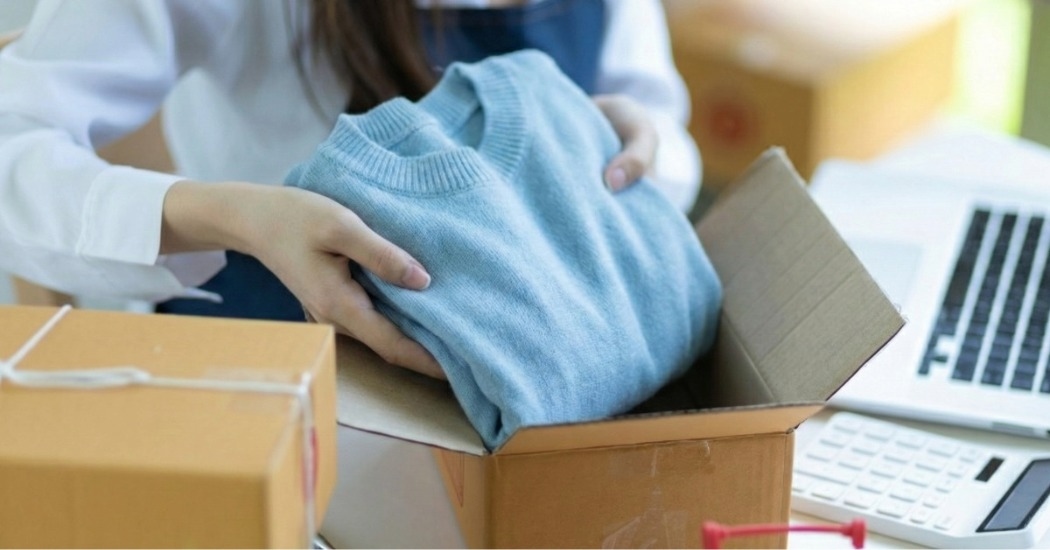 Mulher embala pedido de roupa de loja virtual representando gestão completa de e-commerce